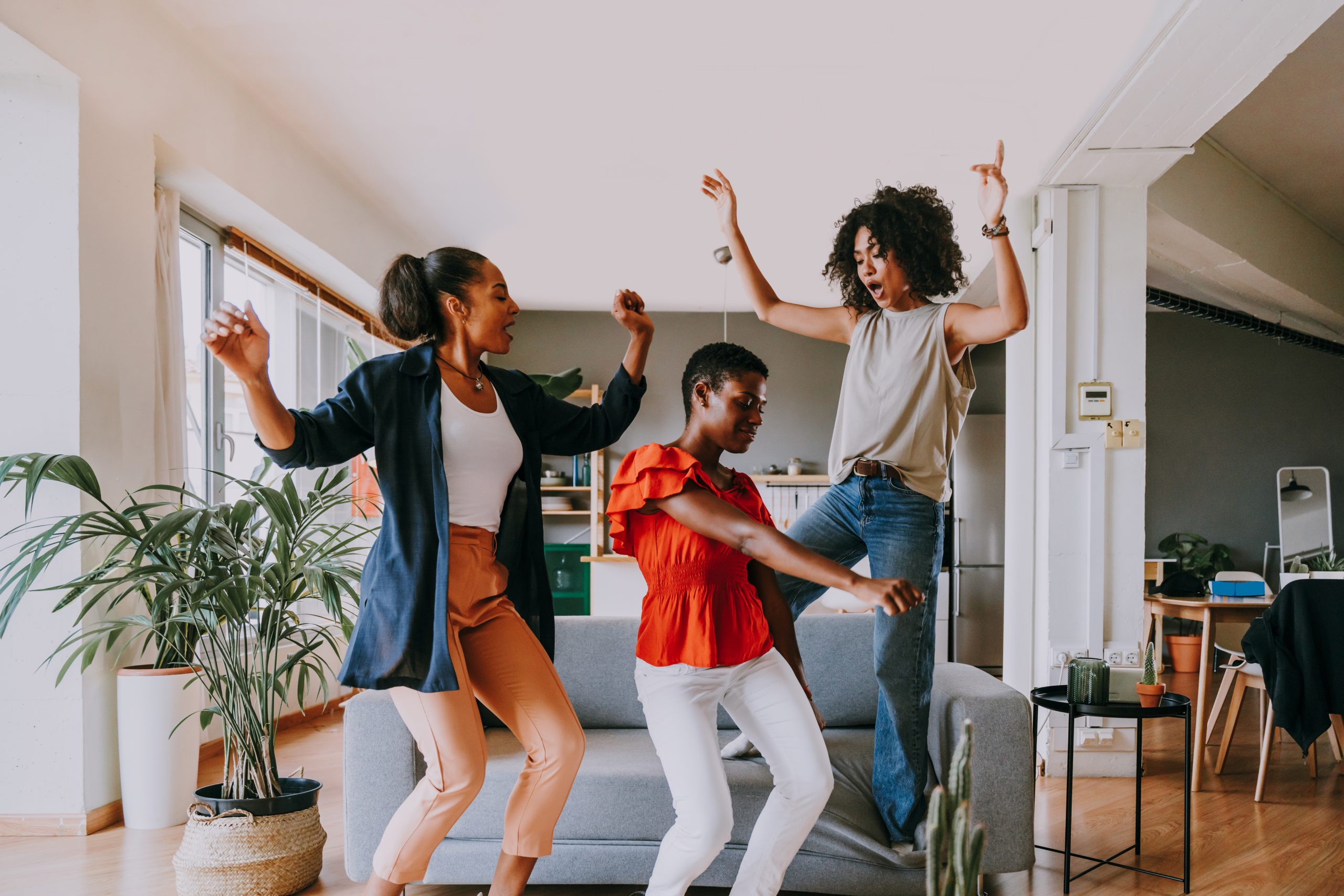 Three women dancing in a living room with wooden floors and modern furniture. 5 simple ways to improve your heart health through movement
